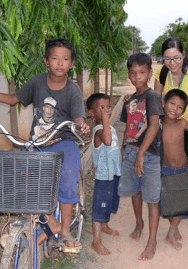 A group of children standing next to a bicycle.